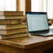 A stack of books next to a laptop, ready for grad school.
