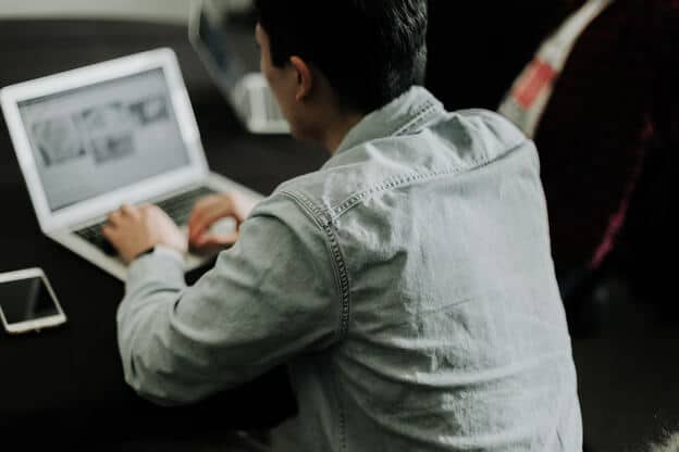 man in dress shirt looking at laptop 