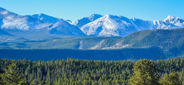landscape view of rocky mountains with forest in foreground
